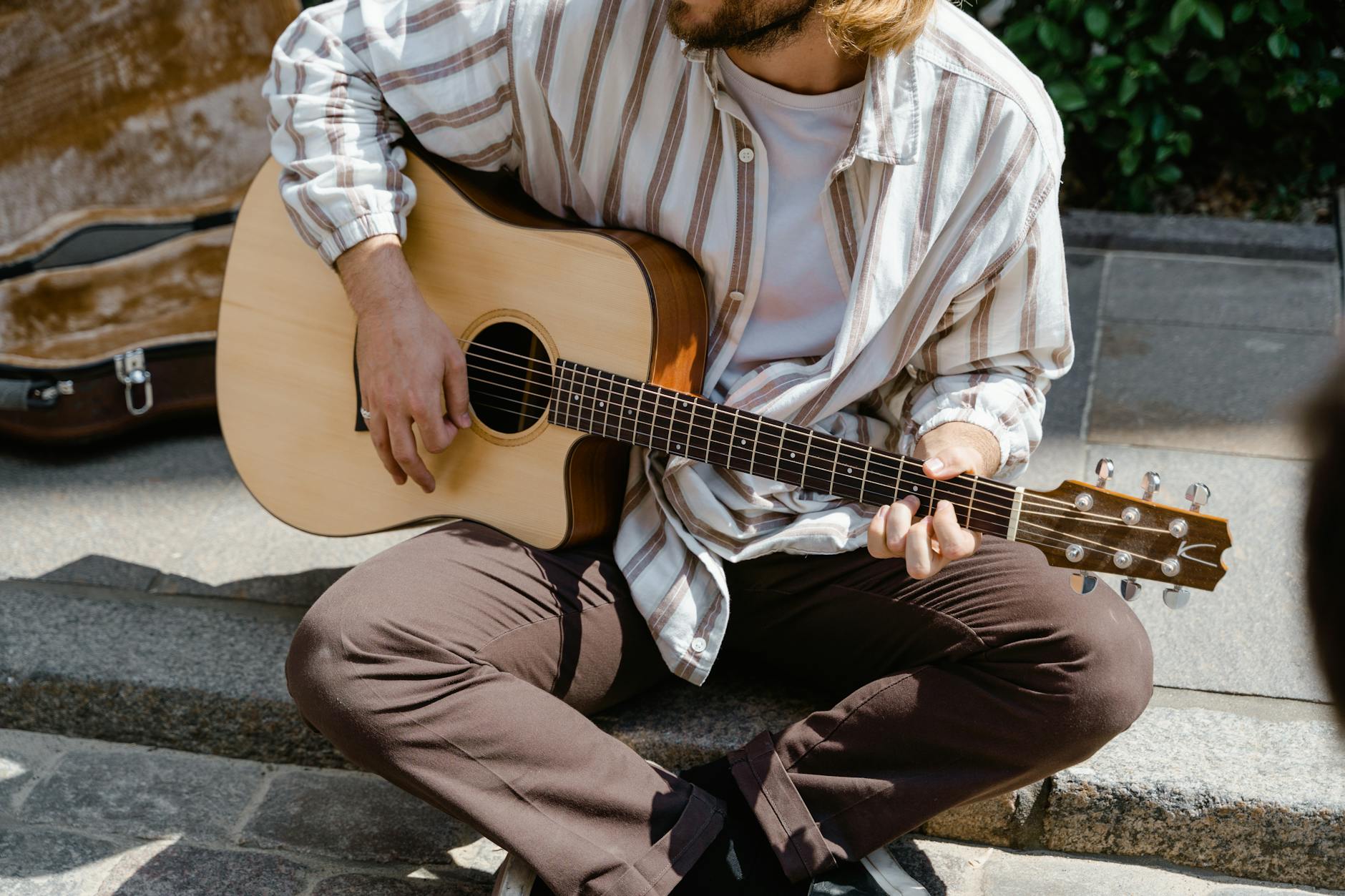 man in white and brown stripe dress shirt playing guitar