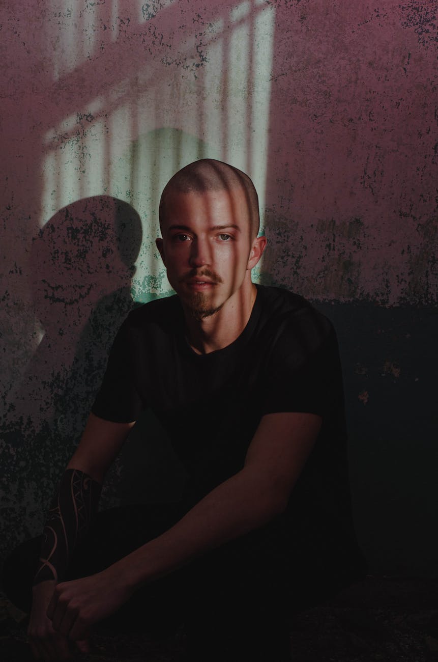 photo of man sitting by the wall