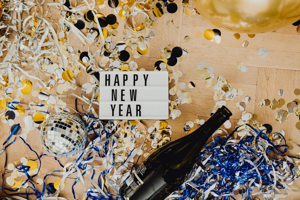 Top view of New Year celebration with champagne, confetti, and lightbox message.